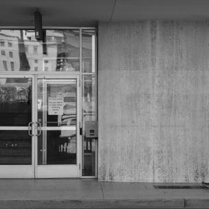 Person walking past a concrete building in black and white