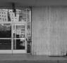 Person walking past a concrete building in black and white